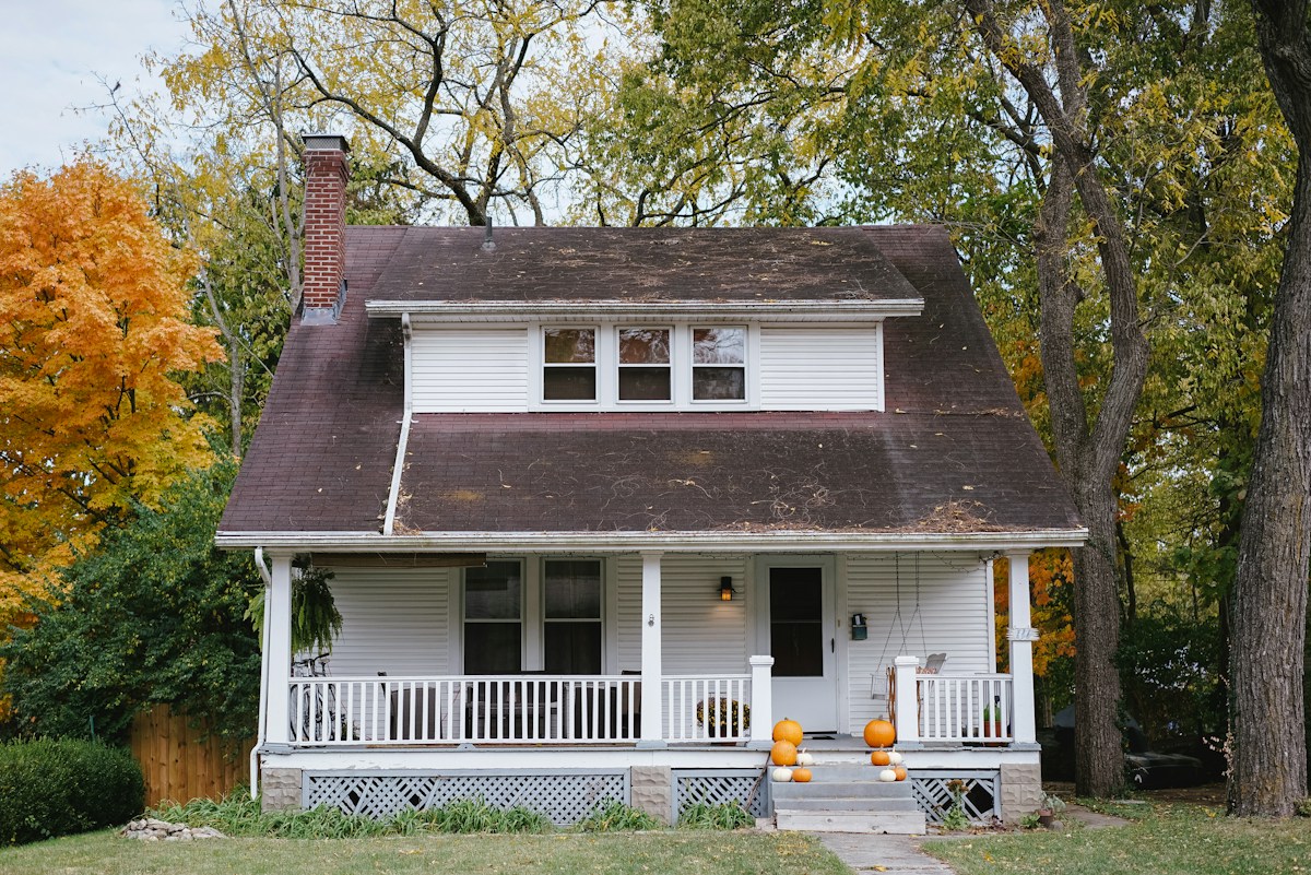 A cozy fall home exterior with mums and pumpkins on the front porch in the Shenandoah Valley